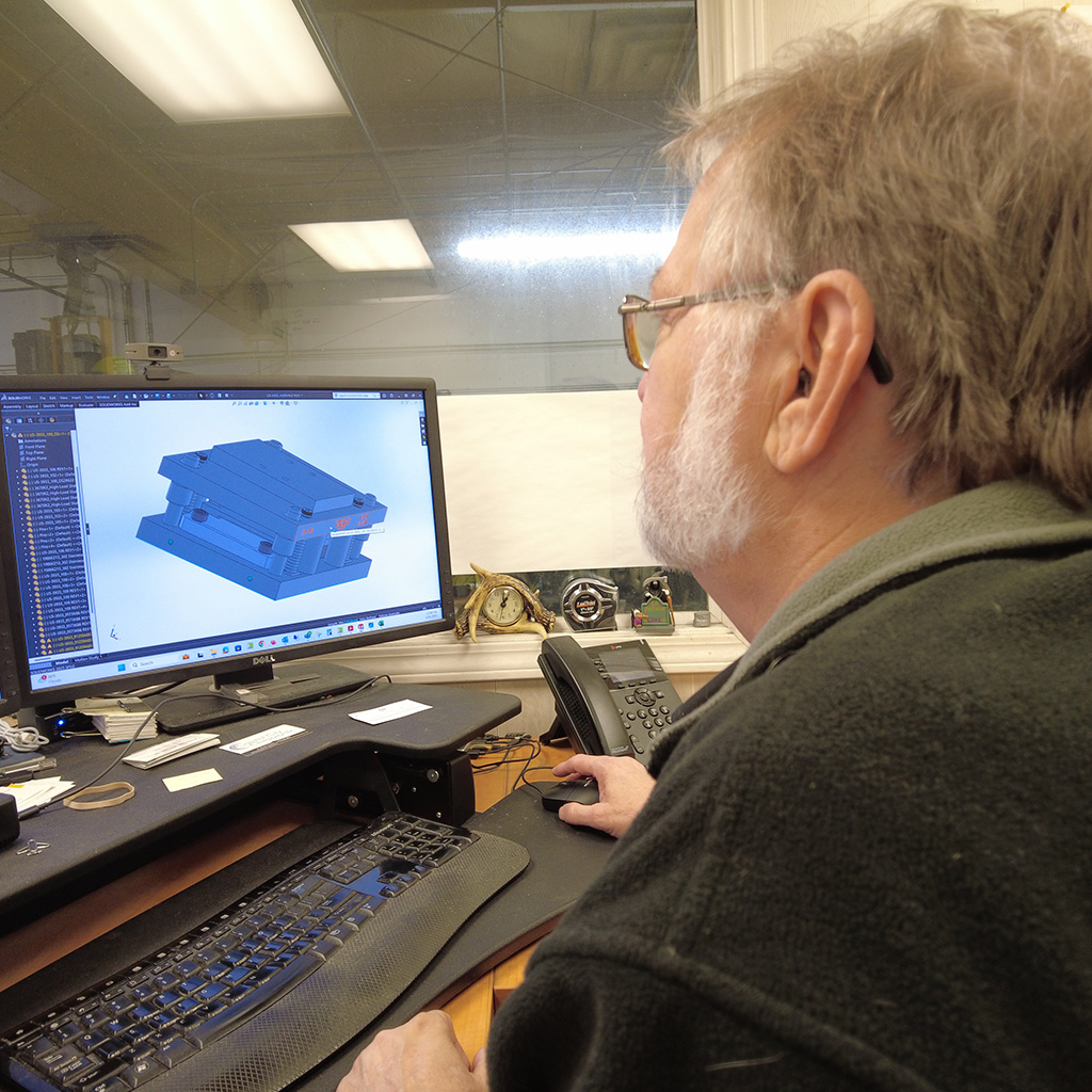 Engineer designing a 3D model of a metal part using CAD software