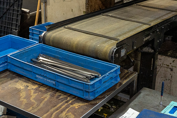 Formed metal parts collected in a container at the end of a conveyor on a Pennant production floor